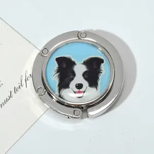 Macro detail of a silver foldable metal purse hook featuring a cute Border Collie dog print