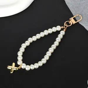 Detailed close-up of an elegant white pearl strap featuring a golden cross pendant and clasp.