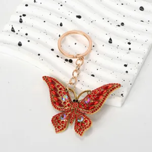 Close-up of a sparkling red rhinestone butterfly keychain on a decorative white prop