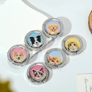 Close-up of foldable metal handbag hooks featuring various cute pet dog and cat designs.