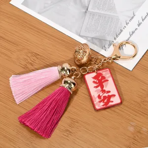 Close-up of tassel keychain with golden hollow palace bell and pink pendant