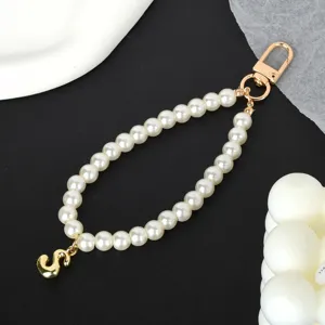 Elegant white pearl phone chain featuring a shiny gold-plated letter S charm pendant