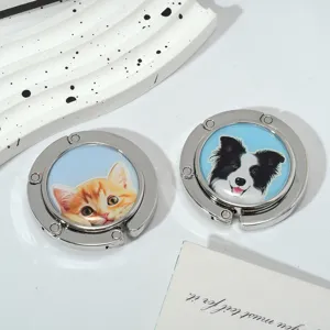 Detailed view of foldable metal purse hooks with cute cat and dog illustrations for desks.