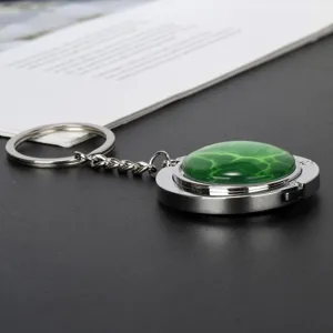 Detailansicht eines silbernen Taschenhalter-Schlüsselanhängers mit grünem Cabochon