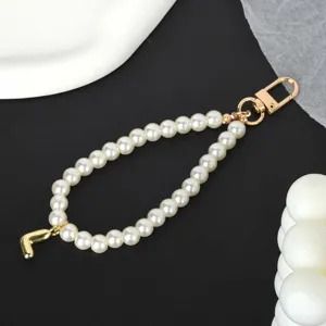 Close-up detail of white pearl phone chain with gold-plated metal clasp and letter J charm