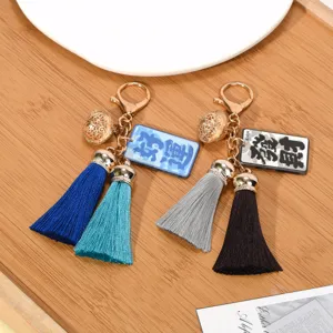 Detailed macro view of two colorful tassel keychains with golden hollow bells and charms