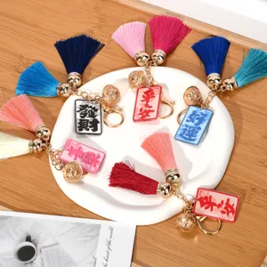 Detailed view of colorful tassel keychains with golden bells and Chinese charms on a plate