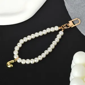 Detail view of elegant white pearl phone strap featuring a gold-tone letter J charm.