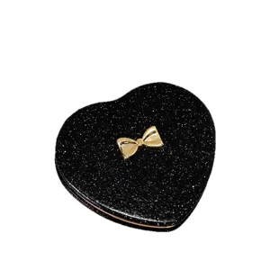 Elegant black heart-shaped folding pocket mirror with a gold bow and glitter finish