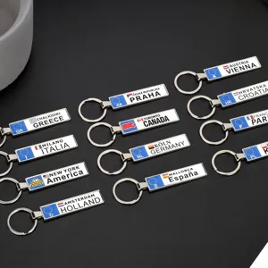 Varietà di portachiavi souvenir in metallo rettangolari con nomi di paesi e città