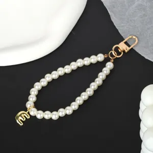 Detail view of pearl phone strap with gold-plated letter E charm and sturdy lobster clasp