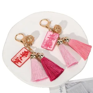 Elegant pink tassel keychain featuring a hollow gold bell and Chinese blessing charms