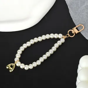 Close-up of an elegant white pearl chain with a golden heart charm and metal clasp