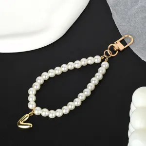 Detailed view of the white pearl chain with a gold-tone 'V' letter charm and metal clasp