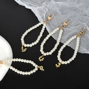 Detailed view of white pearl keychains featuring different golden letter pendants