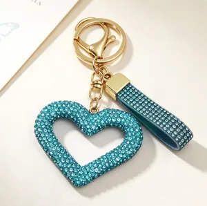 Close-up of turquoise hollow heart keychain with sparkling rhinestones and gold clasp