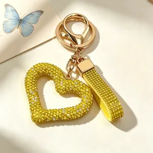 Close-up of yellow rhinestone heart keychain with gold clip and sparkling charm strap.