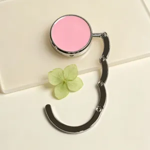 Close-up detail of a portable pink foldable metal bag hook for desk edges and camping