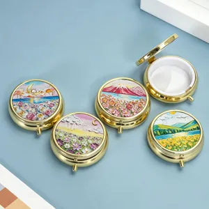 Detailed view of round metal pill boxes with colorful embossed landscape designs