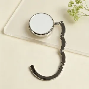 Detailed close-up of a foldable metal handbag hanger hook with a white circular top.
