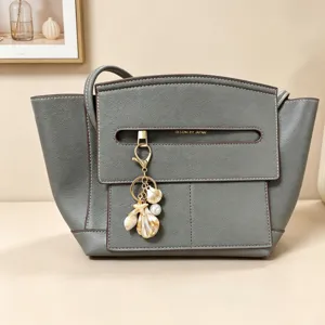 Creative seaside keychain with seashell and starfish charms attached to a leather handbag charm.