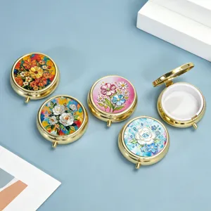 Detailed macro view of vibrant floral embossed patterns on round gold metal pill boxes