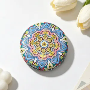 Macro view of portable compact mirror featuring vibrant ethnic mandala pattern and gold