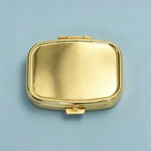 Compact gold metal pill box for medication or jewelry storage, sleek rectangular design.