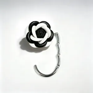 Detail van een opvouwbare tashaken met een stijlvol en elegant zwart-wit camellia-ontwerp