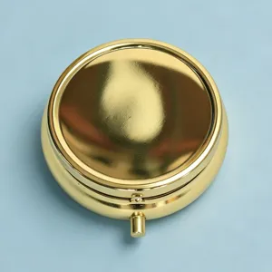 Macro view of a portable golden metal pill box with a secure button latch mechanism.