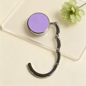 Close-up of a portable purple foldable bag hanger on a clear display plate.
