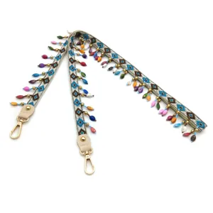 Detail view of ethnic style embroidered bag strap with colorful bead fringe and gold clasp