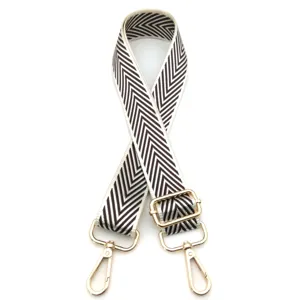 Detalle de la correa ajustable para bolso con patrón de chevron marrón y blanco y clips oro.
