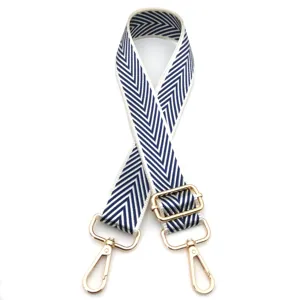Detalle de correa ajustable para bolso con patrón de flechas azules y herrajes dorados.