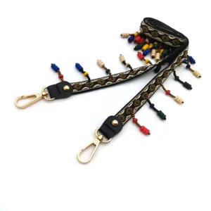 Detail view of bohemian bag strap with ethnic embroidery and colorful beaded tassels