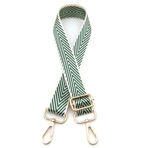 Detalle de correa ajustable para bolso con diseño de espiga verde y blanco y herrajes dorados