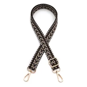Detailed view of an adjustable woven shoulder strap featuring a brown chevron pattern and gold clasps