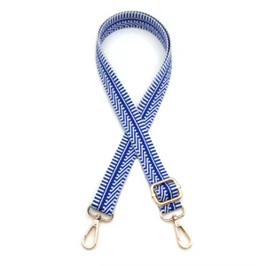 Détail de la bandoulière réglable à motif chevron bleu et blanc avec mousquetons dorés.