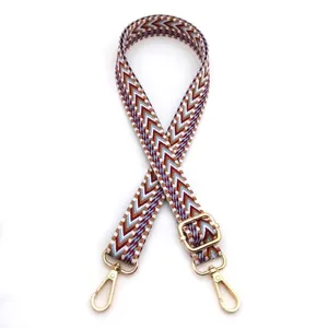 Macro view of the woven chevron patterned adjustable bag strap with gold hardware buckle