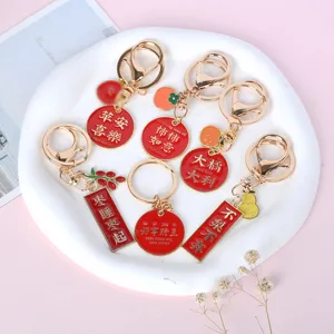Detailed view of red metal blessing keychains with gold-engraved Chinese characters and charms