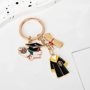 Graduation keychain with golden enamel graduation gown, cap, and diploma charms.