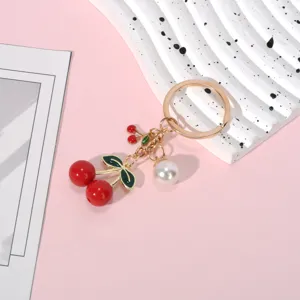 Close-up of a red resin cherry keychain with a white pearl and gold-toned ring