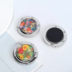 Portable folding silver metal handbag hanger with vibrant floral pattern detail
