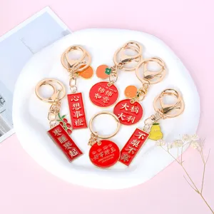 Close-up of metal keychains with red enamel Chinese lucky charms and fruit pendants.