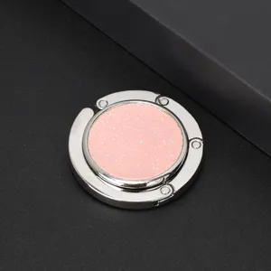Detail of a circular folding purse hook with a pink glitter finish for table sides.