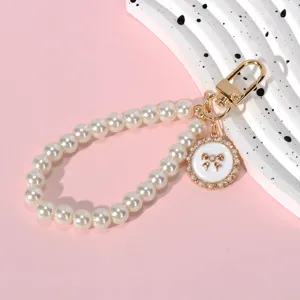 Elegant pearl bead chain keychain featuring a gold lobster clasp and bow pendant