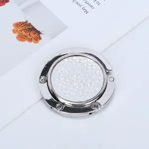 Detailed macro shot of a portable silver folding purse hook with textured inlay for desks