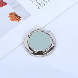 Close-up of portable metal purse hook with light blue pebbled leather insert for desk