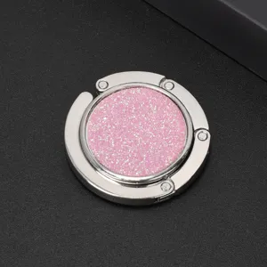 Detail view of portable circular folding bag hook with shimmering pink glitter inlay