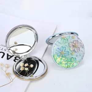 Detail view of portable folding makeup mirror with cherry blossom quicksand cover
